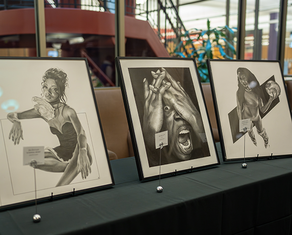 Three framed black and white drawings displayed on table