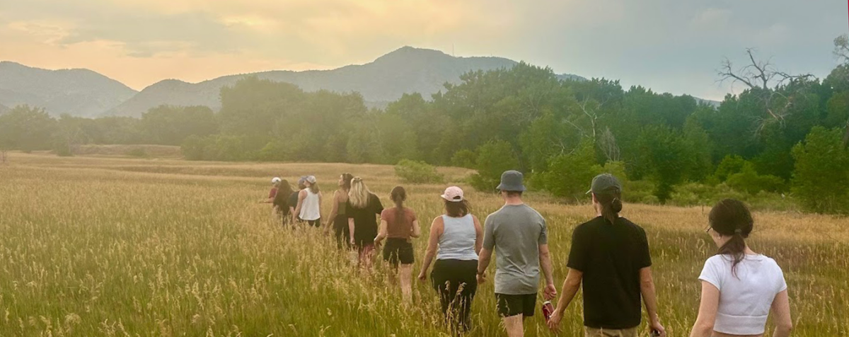 students walking in a line through a field toward mountains on the horizon